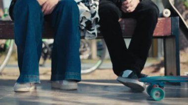 A couple of young people skateboarders paused to drink coffee. A glass of ice latte rides up on a skateboard. Concept of lifestyle, vintage, friendship. High quality 4k footage.