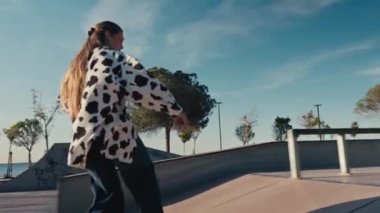 Genç bir kadın kaykay yapıyor, parkta kase oyuyor. Kız yazın kaykay parkında kaykaya biniyor. İzleme görüntüsü