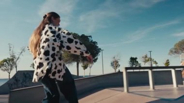 Young woman skateboarding, carving the bowl at the park. Girl rides a skateboarding in a skate park at summer. Tracking shot