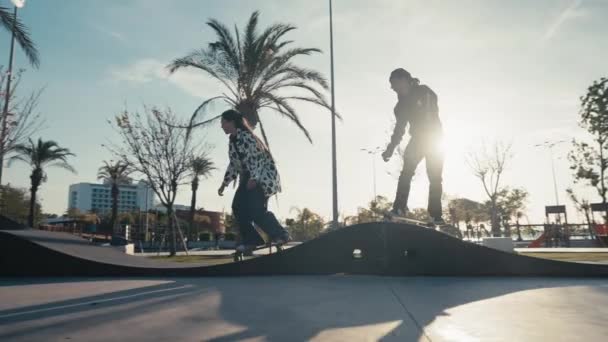 Молода пара катається на скейтборді на трасі або скейт-парку в сучасному стилі. Стеження за тисячолітньою парою фігуристів на трасі насоса — стокове відео