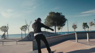 Paten parkında çalışan kaykaycı çocuk. Genç adam kaykay parkında kaykay numaraları yapıyor..