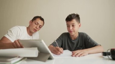 Baba çocuğun ev ödevini yapmasına yardım ediyor. Evde eğitim, mesafe öğrenimi, çevrimiçi eğitim, karantina sırasında çocuklar için uzaktan eğitim ebeveynler için bir sorundur