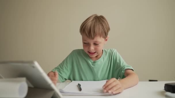 7 Jahre alter Junge sitzt am Tisch im Zimmer und weint, während er an den harten Hausaufgaben arbeitet. Frustrierter kleiner Junge legt Kopf auf Schularbeiten — Stockvideo