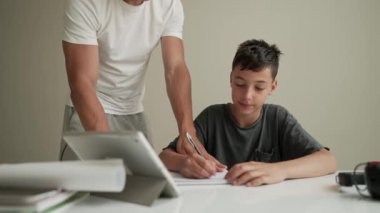 Baba çocuğun ev ödevini yapmasına yardım ediyor. Evde eğitim, mesafe öğrenimi, çevrimiçi eğitim, karantina sırasında çocuklar için uzaktan eğitim ebeveynler için bir sorundur