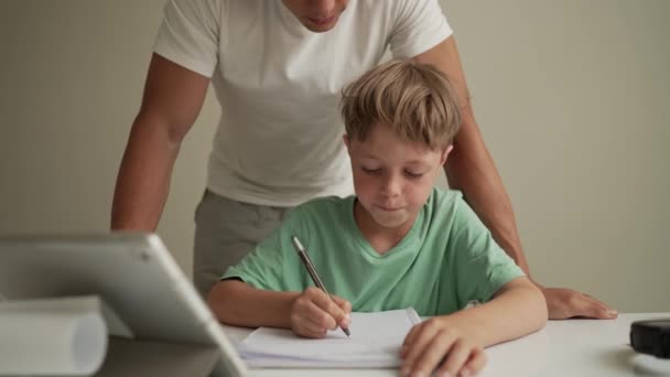 Baba çocuğun ev ödevini yapmasına yardım ediyor. Evde eğitim, mesafe öğrenimi, çevrimiçi eğitim, karantina sırasında çocuklar için uzaktan eğitim ebeveynler için bir sorundur — Stok video
