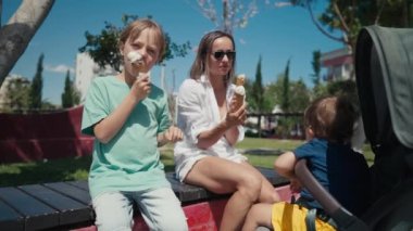 Oğlumla güzel bir gün. Yazın küçük bir çocukla birlikte dışarıda dondurma yiyen genç bir anne. Yaz yemeği ve yaz tatili.