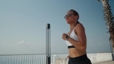 Genç beyaz kadın deniz kenarında koşuyor. Spor giyimli sıska kız deniz kenarında geziniyor..