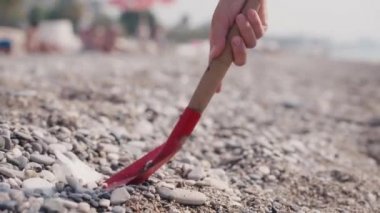 Gönüllü bir kadın plaj petrolünde kıyıya vurmuş petrolü temizlemeye çalışıyor.