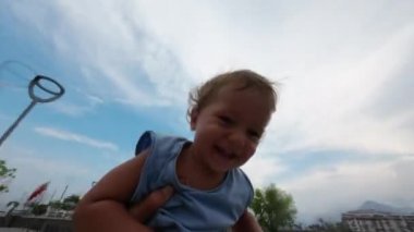 Baba parkta oğluyla oynuyor. Babası sevimli küçük oğlunun etrafında dönüyor.