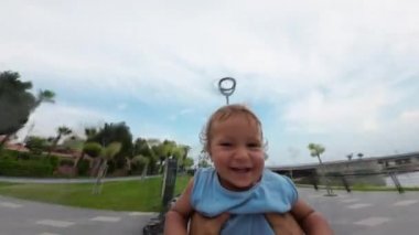 Baba parkta oğluyla oynuyor. Babası sevimli küçük oğlunun etrafında dönüyor.