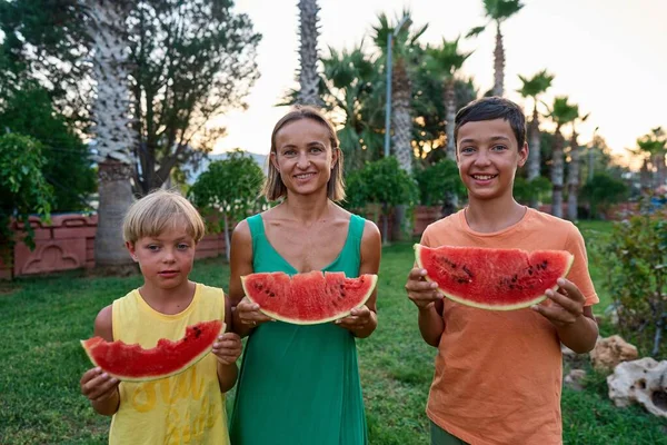 Dulce Familia Madre Sus Hijos Comiendo Sandía Aire Libre Divirtiéndose Imagen de archivo