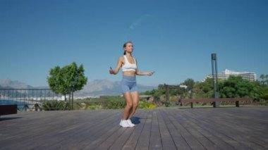 Kadın iki ip atlayarak atlıyor ve plajda egzersiz yapıyor. Yüksek kalite 4k görüntü