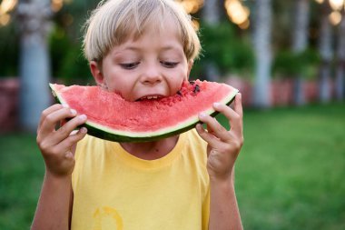 Bahçede sağlıklı organik karpuz yiyen tatlı çocuk, doğa arka planı, güneşli ışıklar. Yüksek kalite fotoğraf