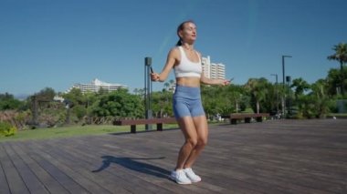 Kadın iki ip atlayarak atlıyor ve plajda egzersiz yapıyor. Yüksek kalite 4k görüntü