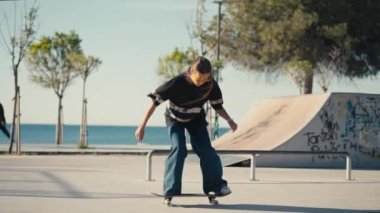 Genç bir kadın kaykay yapıyor, parkta kase oyuyor. Kız yazın kaykay parkında kaykaya biniyor. İzleme görüntüsü. Yüksek kalite 4k görüntü