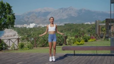 Genç bir kadın ip atlıyor. Genç bayan atlet ip atlıyor, açık havada sağlıklı olmak için antrenman yapıyor. Yavaş çekim