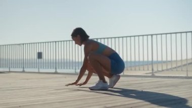 Şehirli bir sokakta güneşli bir sabahta genç kaslı bir kadın göğüs çalışıyor. Ağaçların yanındaki bankta şınav çeken çarpıcı kızın hareketini yakından izleyin. Sağlıklı yaşam tarzı kavramı. Yüksek kalite 4k görüntü