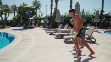 Suya atlayan kardeşler. İki çocuk yüzme havuzuna atlarken eğleniyor..