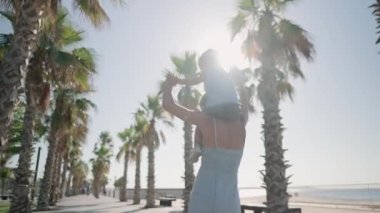 Young beautiful mother holds a 2 year old sweet son. Walk in the summer at the beach . carries on the shoulders a close-upHigh quality 4k footage