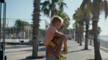 Baby sitting on mother shoulders outside at park. High quality 4k footage