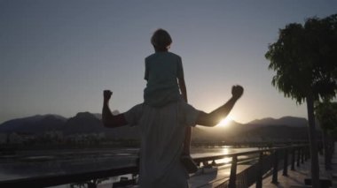 Happy family silhouette teamwork kid dream concept . son boy superhero sitting on his father man neck. happy family father and kid son silhouette dream. High quality 4k footage