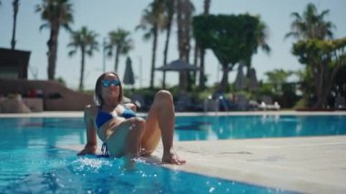 Cute beautiful girl sitting near the pool. Summer vocation.