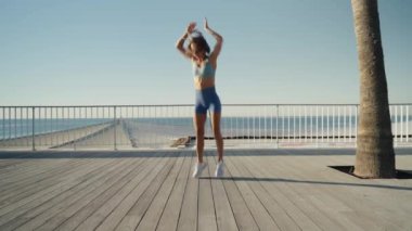 Sporcu kadın deniz kenarında spor yapıyor. Burpee egzersizi yapıyor. Yüksek kalite 4k görüntü