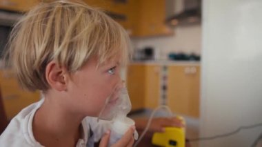 Child has respiratory infection or bronchitis, and he is breathing heavily. Blond Caucasian child with asthma problems inhales with tube in his mouth.High quality 4k footage