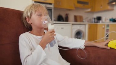 Child has respiratory infection or bronchitis, and he is breathing heavily. Blond Caucasian child with asthma problems inhales with tube in his mouth.High quality 4k footage
