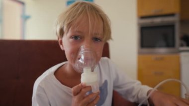 Child has respiratory infection or bronchitis, and he is breathing heavily. Blond Caucasian child with asthma problems inhales with tube in his mouth.High quality 4k footage