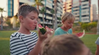 Four school children eating watermelon outdoor at summer time, happy summer concept. High quality 4k footage
