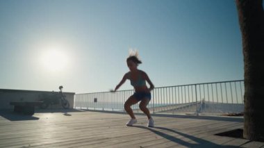 Sporcu kadın deniz kenarında spor yapıyor. Burpee egzersizi yapıyor. Yüksek kalite 4k görüntü