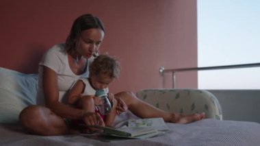 Happy family mother and son read a book in the evening at home
