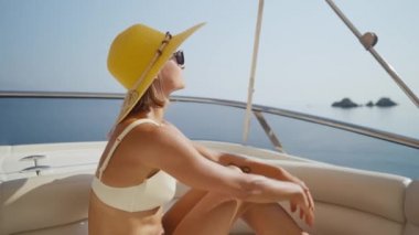 Beautiful woman wearing straw hat and white bikini on a yacht enjoys the journey. High quality 4k footage