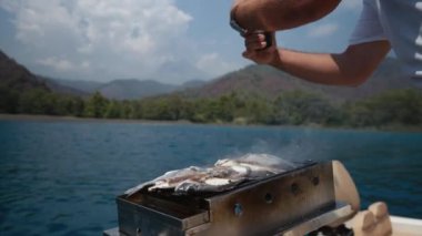 Closeup of preparing grilled sea bass fish outdoors in the open sea, while traveling by boat, slow motion. High quality 4k footage