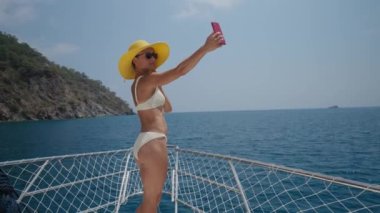 Young woman taking photo selfie on bow of yacht and she look happy. Concept of holiday at sea or beach by boat with nature traveling. High quality 4k footage