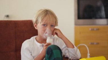 Child has respiratory infection or bronchitis, and he is breathing heavily. Blond Caucasian child with asthma problems inhales with tube in his mouth.High quality 4k footage