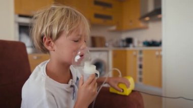 Child has respiratory infection or bronchitis, and he is breathing heavily. Blond Caucasian child with asthma problems inhales with tube in his mouth.High quality 4k footage