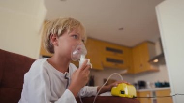 Child has respiratory infection or bronchitis, and he is breathing heavily. Blond Caucasian child with asthma problems inhales with tube in his mouth.High quality 4k footage