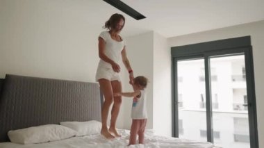 Mutlu anne, oğlunla yatakta zıplarken iyi eğlenceler. Yavaş çekim
