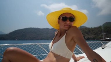 Beautiful woman wearing straw hat and white bikini on a yacht enjoys the journey. High quality 4k footage