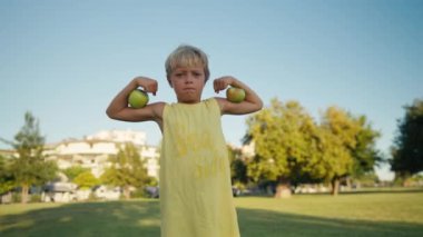 Funny boy with red apples shows biceps. High quality 4k footage