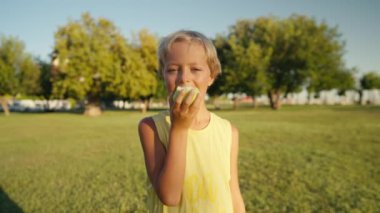 Cute child boy portrait stay in apple tree garden outdoors eating green juicy apple. High quality 4k footage