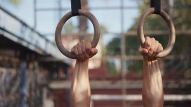 Muscular athletic young man exercising on gymnastic rings. Sport and health care concept. High quality 4k footage