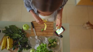 Young sportswoman putting washed greenery on table, and cooking smoothie. Happy vegetarian cooking healthy food and dancing. High quality 4k footage
