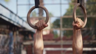 Muscular athletic young man exercising on gymnastic rings. Sport and health care concept. High quality 4k footage