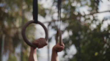 Muscular athletic young man exercising on gymnastic rings. Sport and health care concept. High quality 4k footage