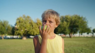 Cute child boy portrait stay in apple tree garden outdoors eating green juicy apple. High quality 4k footage