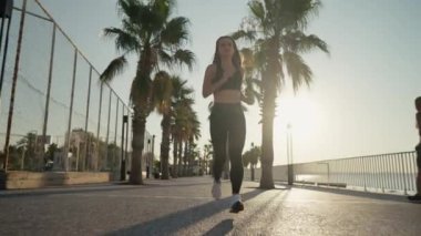 Young active woman jogging along beautiful beach. Running happy woman enjoying their summer morning workout. High quality 4k footage