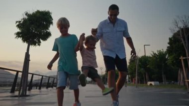 Father and Son Holding Hands Walking Together with little brother on the Beach at Sunset